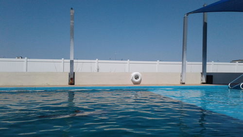 Sailboats in swimming pool against clear blue sky