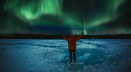 Rear view of man standing in frozen lake at night