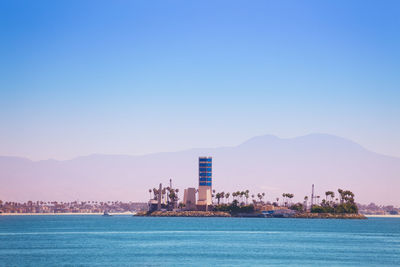 Sea by buildings against clear blue sky