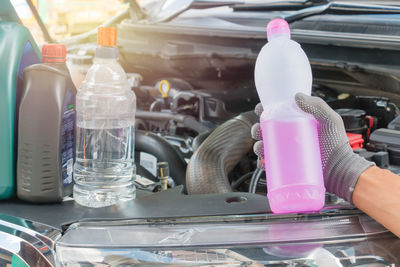 Cropped image of hand holding bottle on vehicle