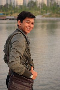 Portrait of young man standing against lake