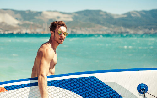 Portrait of young man carrying surfboard