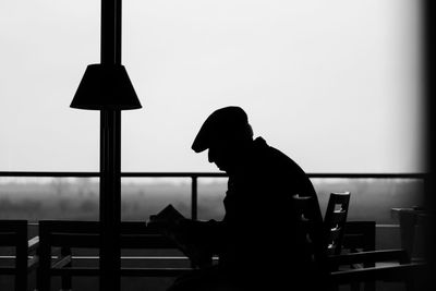 Side view of silhouette man using smart phone against sky