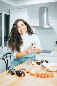 Portrait of smiling woman using phone at home