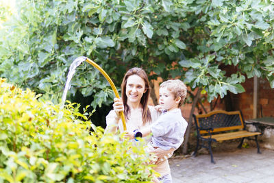 Portrait of smiling young woman against plants