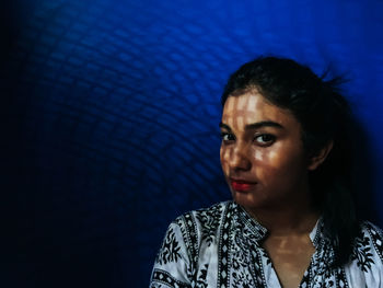 Close-up of young woman against black background