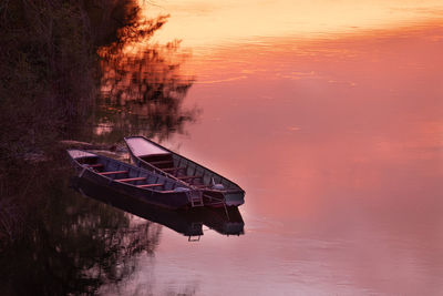 Boat moored in lake against sky during sunset