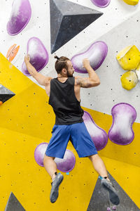 Full length rear view of man standing against multi colored wall