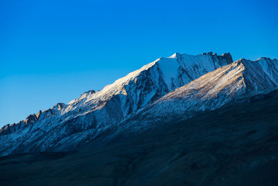 Scenic view of snowcapped mountains against clear blue sky