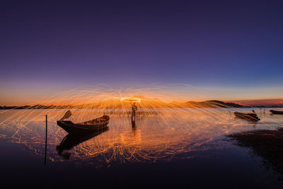 Man with wirewool amidst sea during sunset