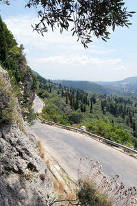 Road amidst trees and landscape against sky