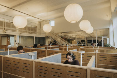 Young female wearing headphones student studying in library at university