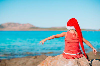 Rear view of woman on beach against sky