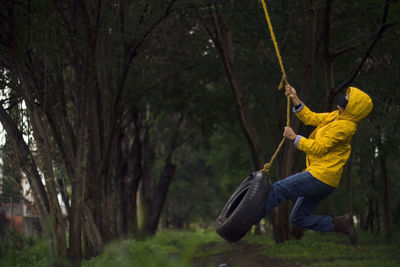 Man holding rope against trees in forest