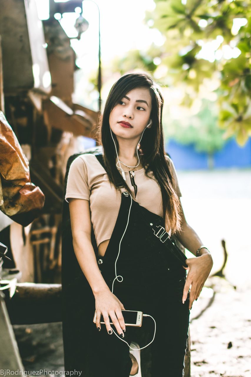 PORTRAIT OF BEAUTIFUL YOUNG WOMAN STANDING AGAINST WALL