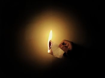 Close-up of hand holding burning candle
