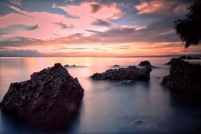 Rocks on sea against sky during sunset