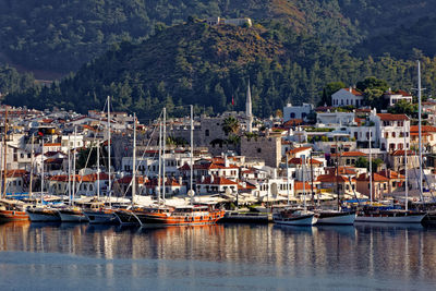 Sailboats moored in harbor by buildings in city