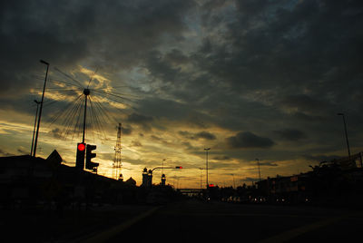 Cars on road against dramatic sky at sunset