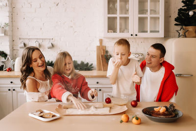 Family with children having fun and laughing while preparing for the christmas holiday in kitchen