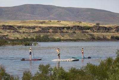 Two friends watch a young man jump off a dock in the columbia river.