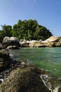 Rocks by sea against clear sky