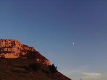Low angle view of rocks against clear blue sky