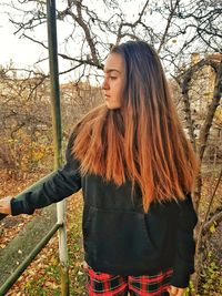 Woman with long hair standing by railing