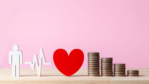 Close-up of heart shape on pink table against gray background