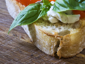 Close-up of bruschetta sandwich with feta cheese and basil on cutting board