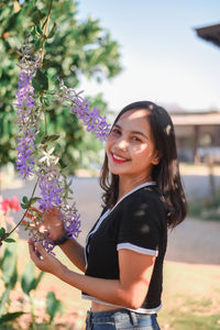 Portrait of smiling young woman standing against sky