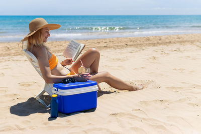 Rear view of woman sitting at beach