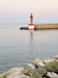 Lighthouse by sea against sky