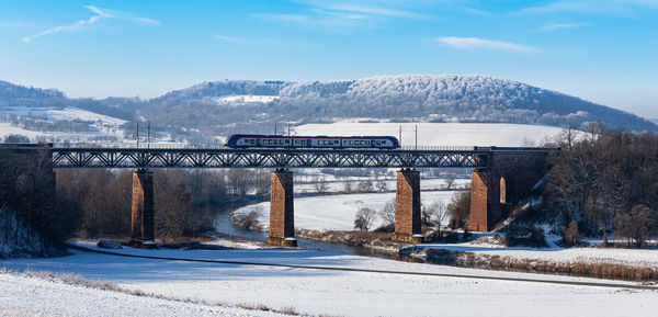 Winter landscape and railway bridge with train crossing