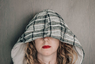 Curly woman with a hood on her head covering her eyes