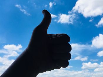 Low angle view of human hand against sky