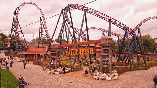 People at amusement park ride against sky