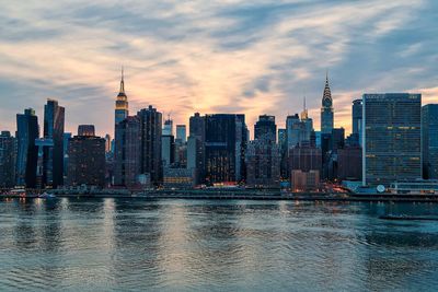 View of buildings at waterfront against cloudy sky