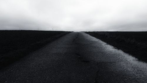 Road amidst agricultural field against sky