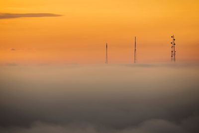 Smoke stacks against sky during sunset