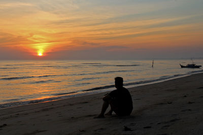 Man on beach against sky during sunset