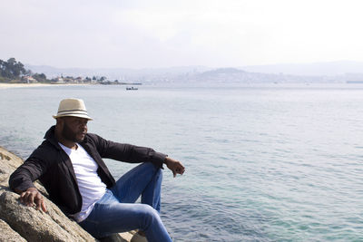 Man sitting in sea against sky