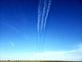 Low angle view of three vapor trails against blue sky