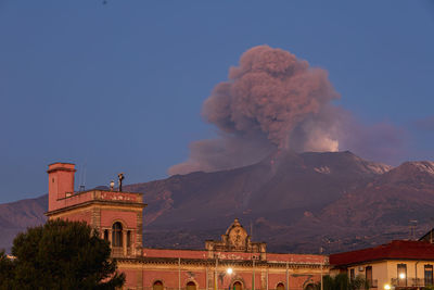 Low angle view of the cityscape against the sky during the strombolian eruption of etna