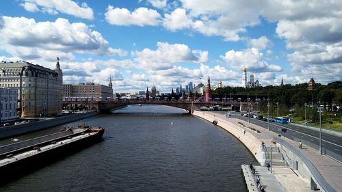 Bridge over river amidst buildings in city against sky