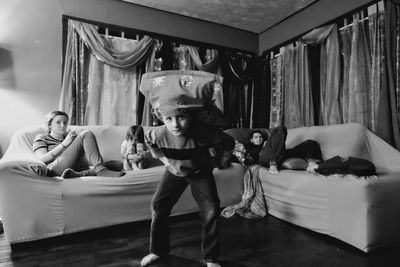 Siblings looking at boy playing with pillow case at home