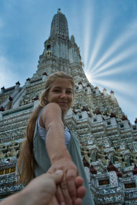 Portrait of smiling young woman against building