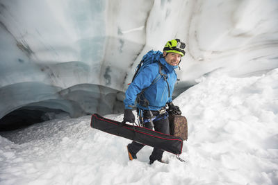 Scientist carries gear out of a glacier cave, british columbia, canada