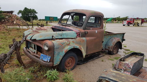 Abandoned car on field against sky