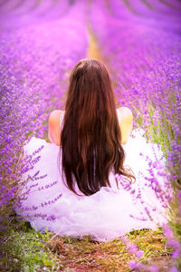 Rear view of woman sitting on purple flower